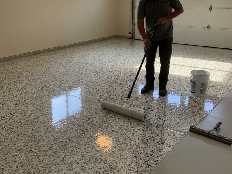 Coating crew applying a polyaspartic floor coating in a San Diego garage with high-gloss finish